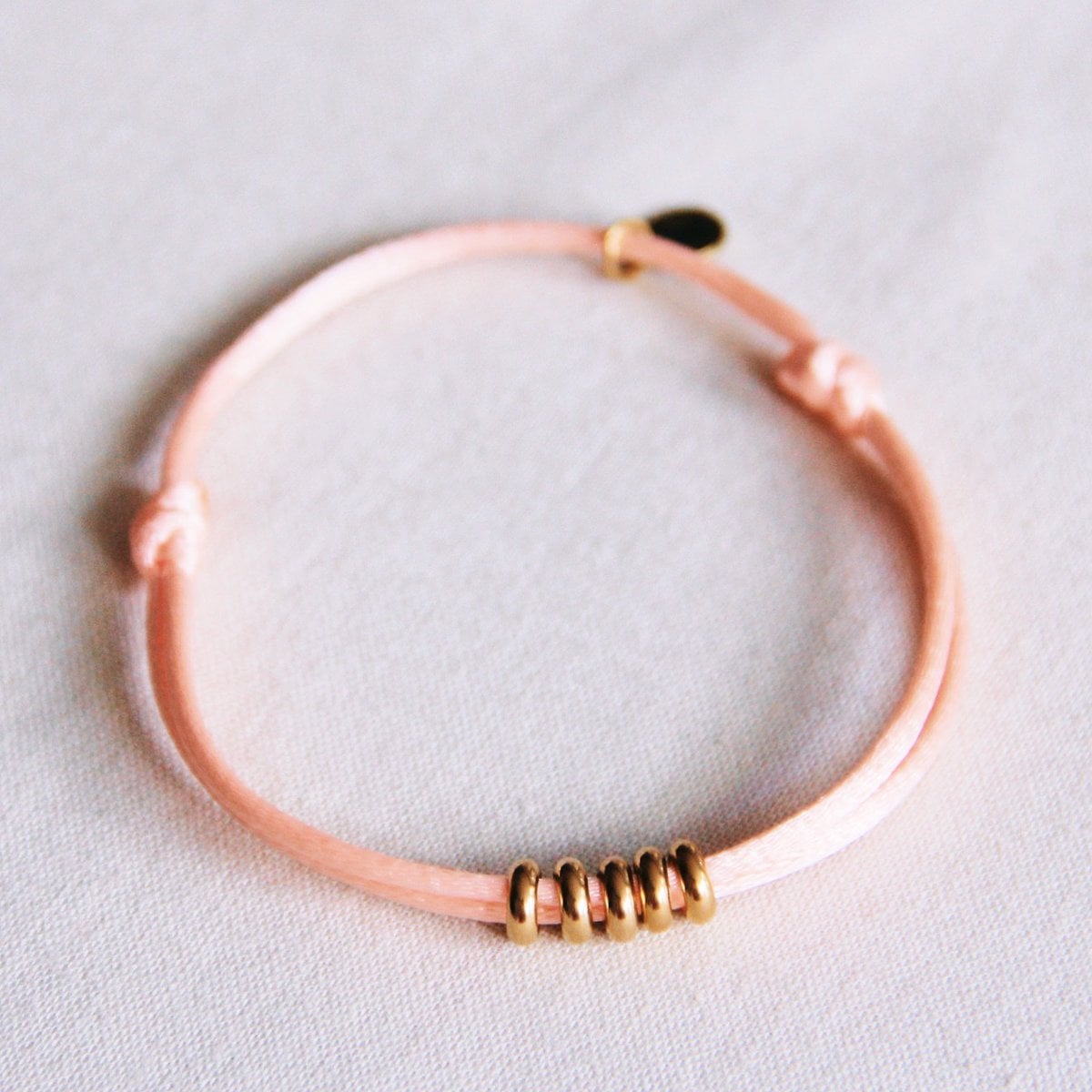 Satijnen armband met ringen - zalm/goud